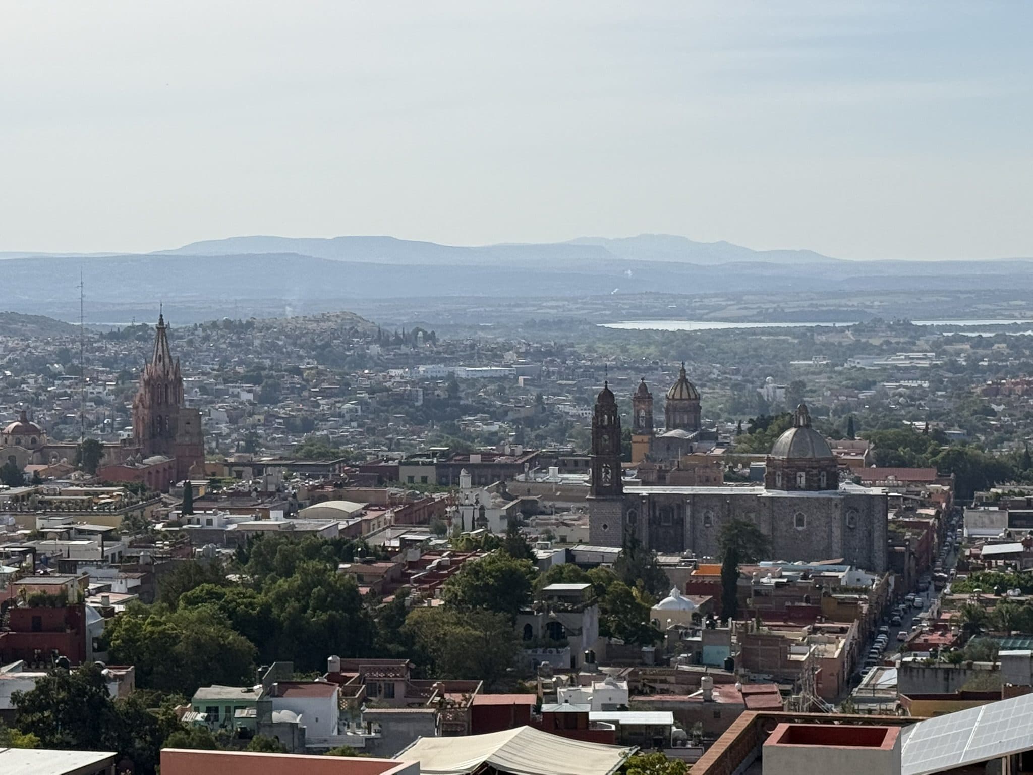 San Miguel de Allende from above, its church towers rising over the town toward distant mountains